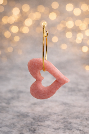 Handgemachte Creolen mit rosa Polymer-Clay-Anhänger in Schleifenform auf Schmuckständer