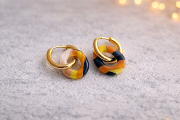 Handgemachte Statement-Creolen mit gelb-schwarz gemustertem Polymer-Clay-Anhänger auf Schmuckständer