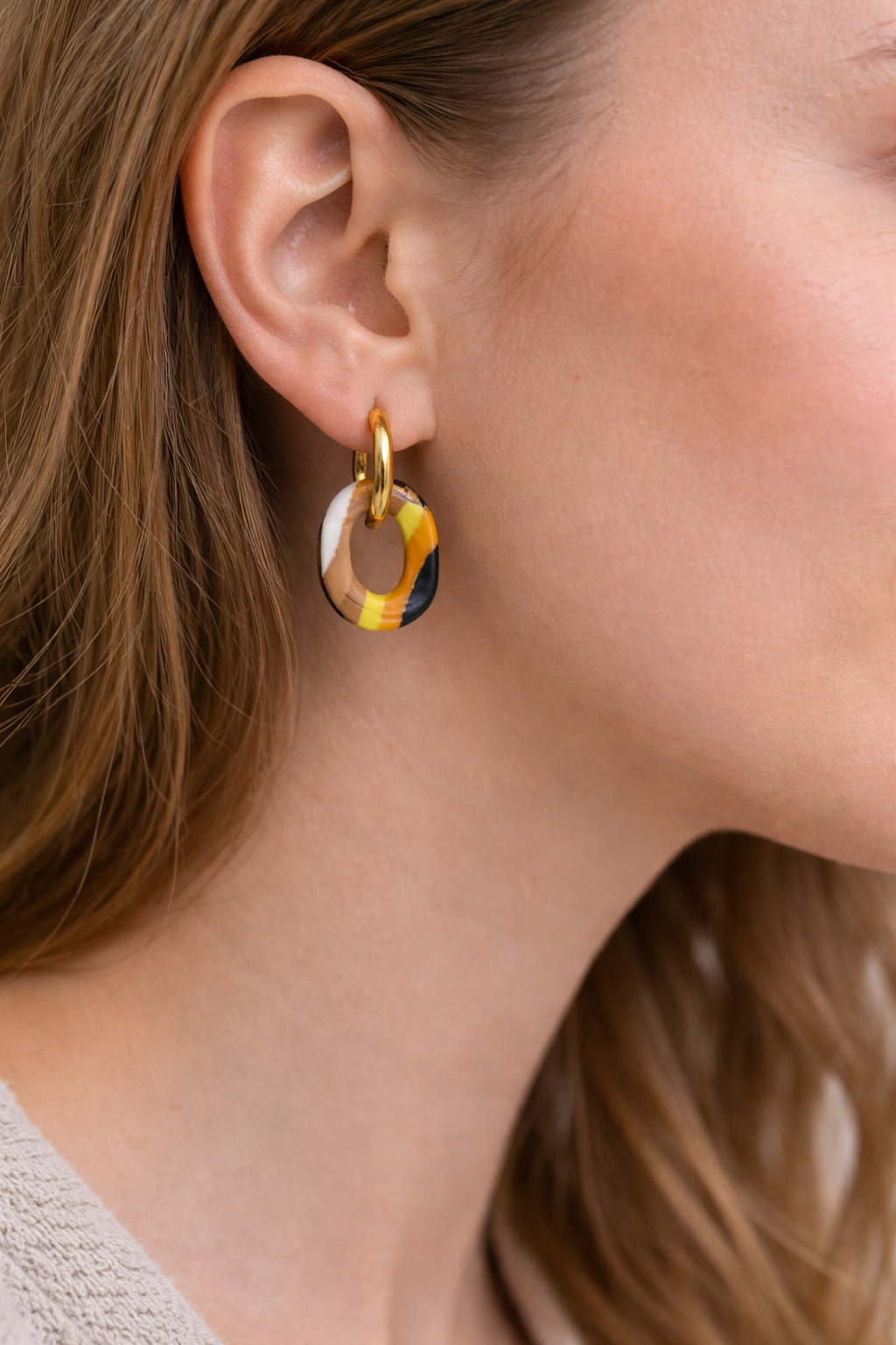 Handgemachte Statement-Creolen mit gelb-schwarz gemustertem Polymer-Clay-Anhänger auf Schmuckständer