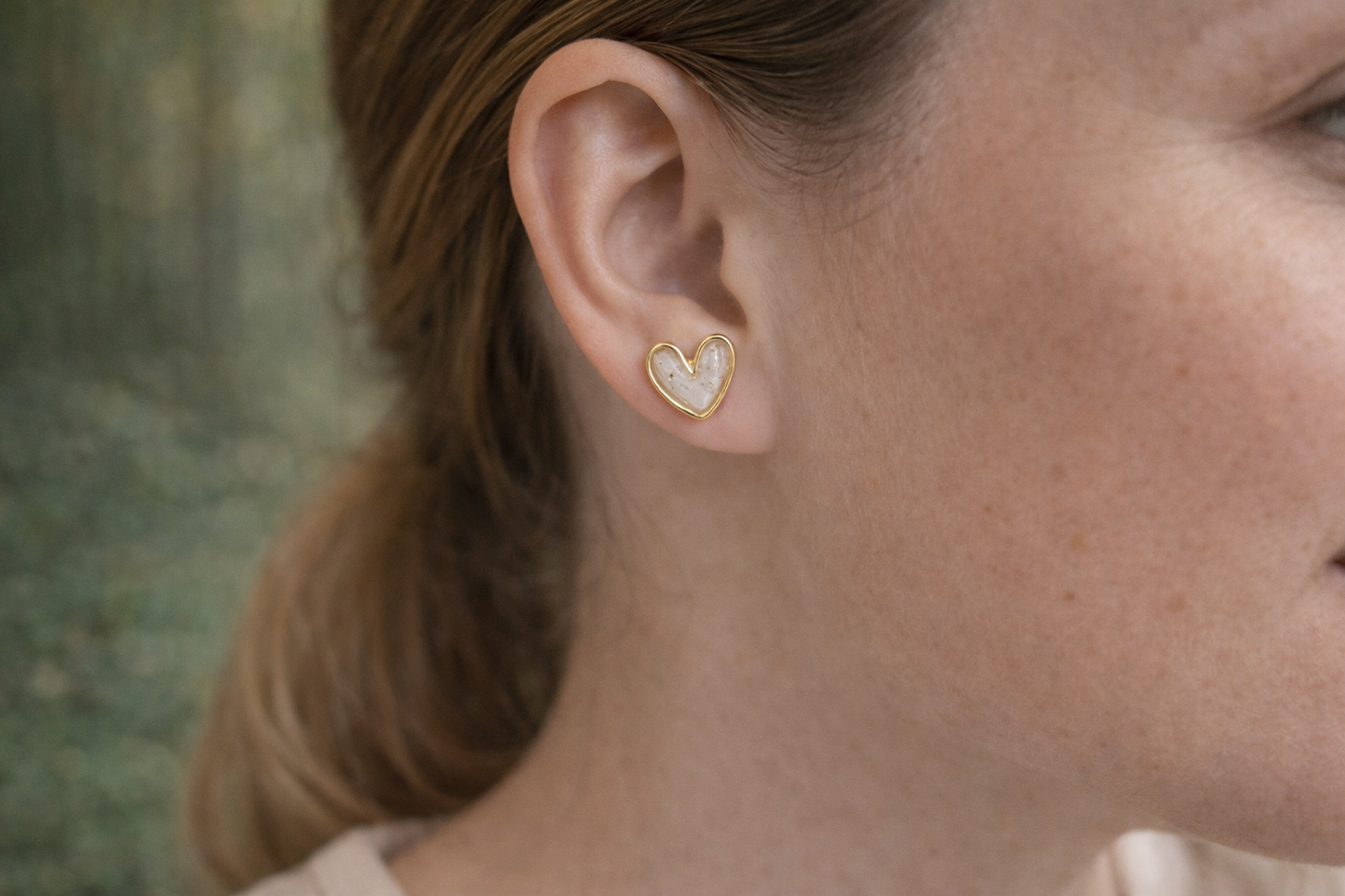 Zarte Herz-Ohrstecker aus Polymer Clay in Weiß mit goldener Umrandung, getragen von einer Frau – minimalistisch und elegant.