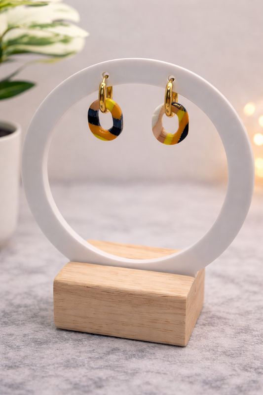 Handgemachte Statement-Creolen mit gelb-schwarz gemustertem Polymer-Clay-Anhänger auf Schmuckständer