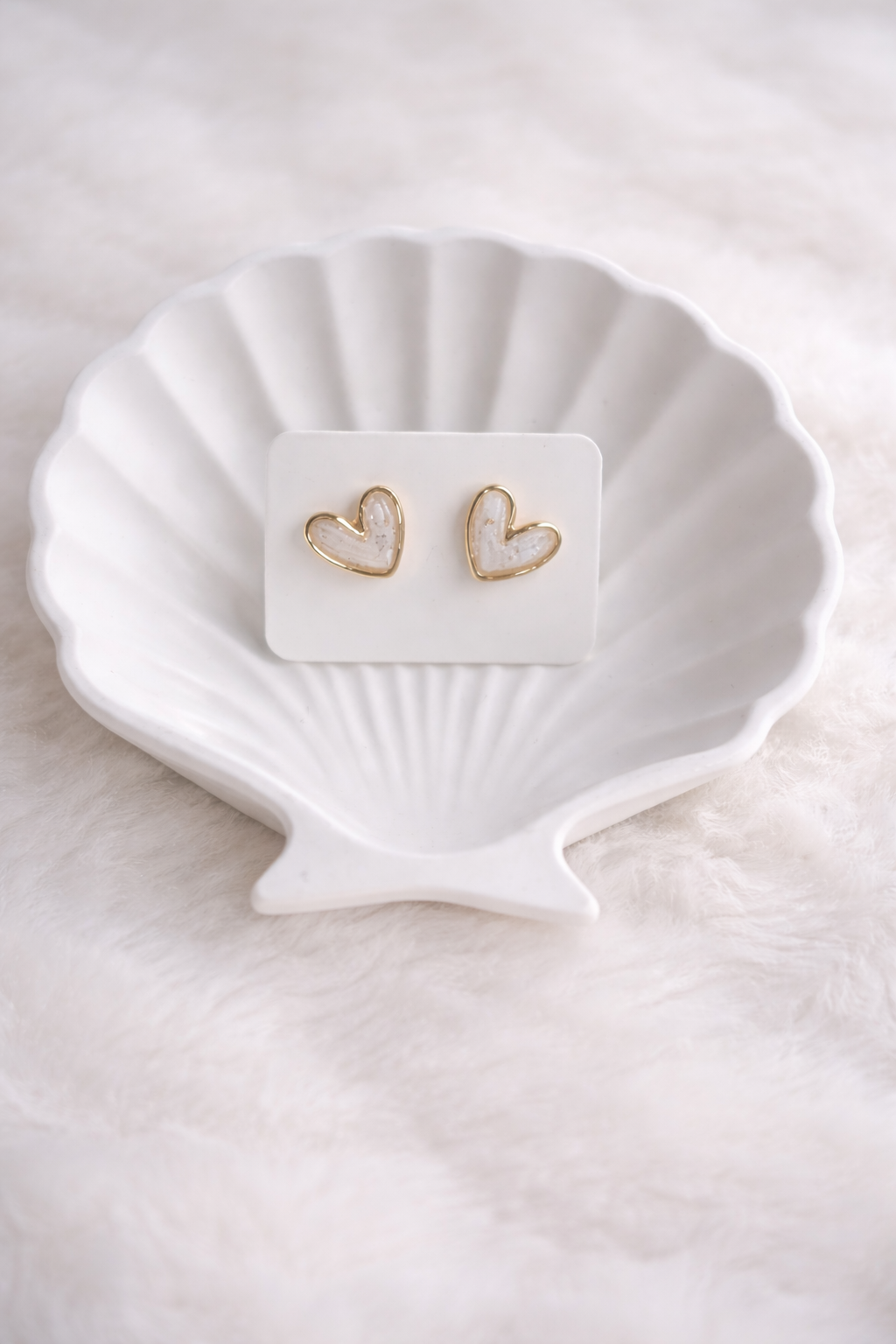 Zarte Herz-Ohrstecker aus Polymer Clay in Weiß mit goldener Umrandung, getragen von einer Frau – minimalistisch und elegant.