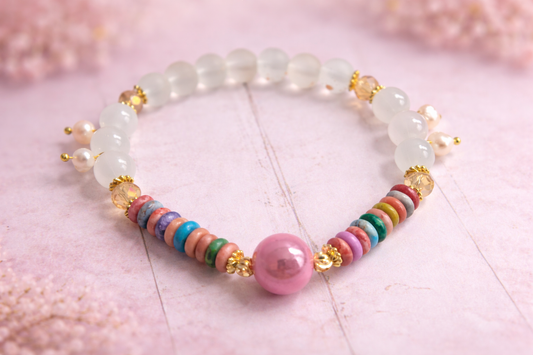 Handgemachtes Perlenarmband mit weißen Glasperlen, bunten Keramikperlen und goldenen Akzenten auf hellem Hintergrund