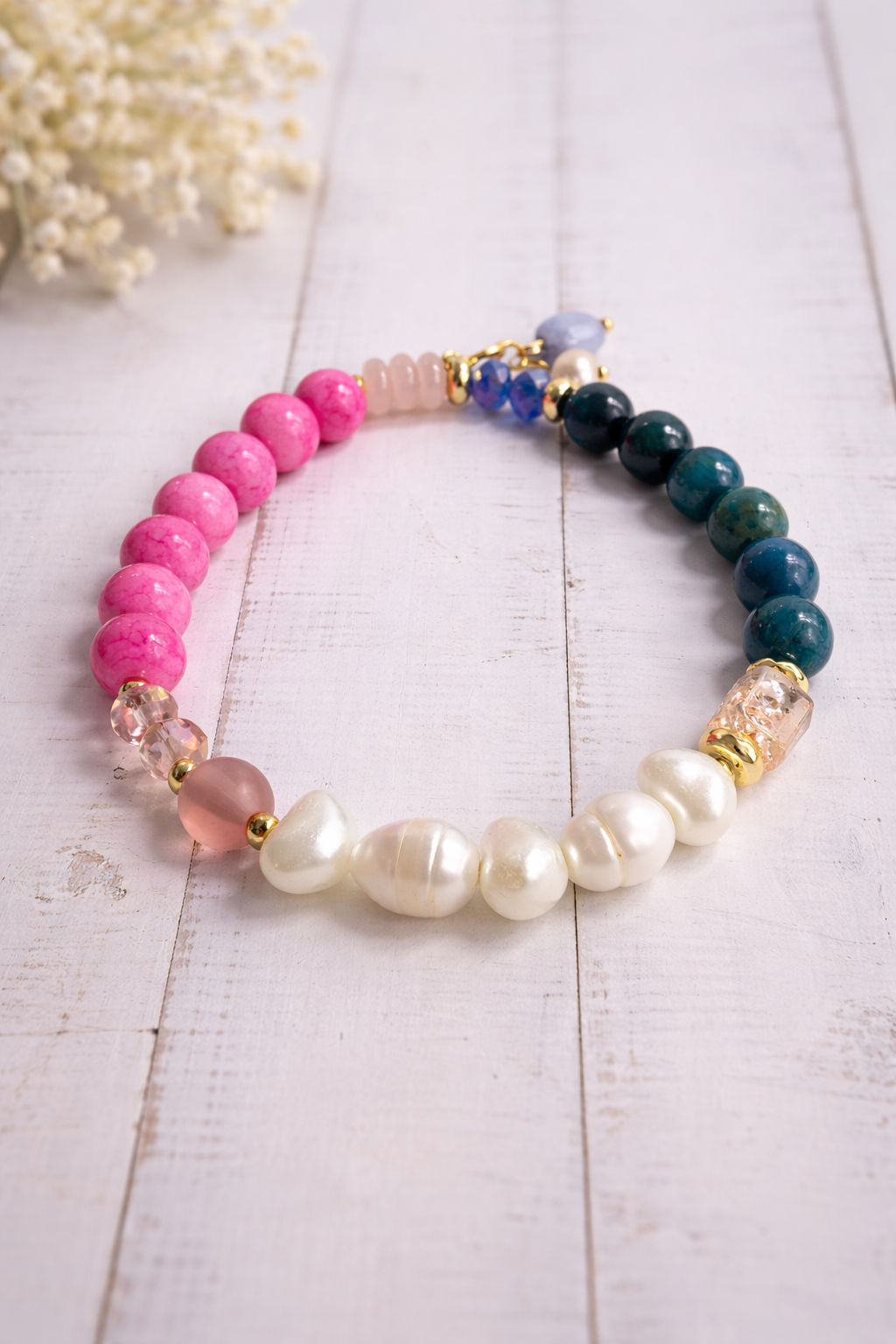 Handgemachtes Armband mit bunten Perlen im Farbverlauf aus Rosa, Blau, Grün und Weiß auf hellem Hintergrund